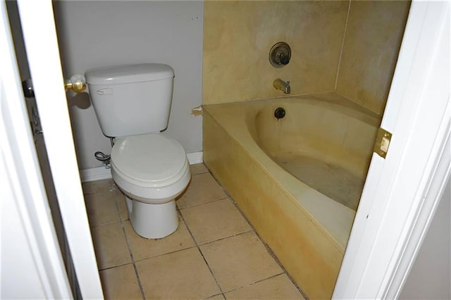 bathroom featuring a tub to relax in, tile patterned floors, and toilet