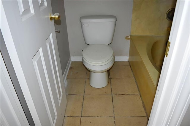 bathroom featuring tile patterned flooring, a bath, and toilet