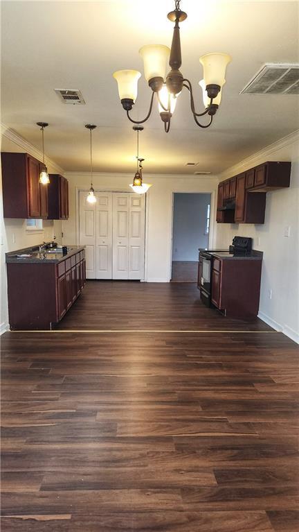 kitchen featuring black electric range, ornamental molding, dark hardwood / wood-style flooring, decorative light fixtures, and a chandelier