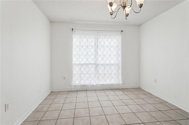 spare room featuring a textured ceiling and a chandelier