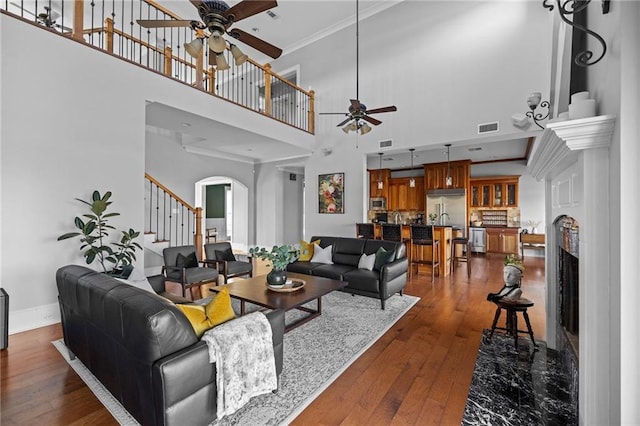 living room featuring sink, a high ceiling, ornamental molding, ceiling fan, and dark wood-type flooring