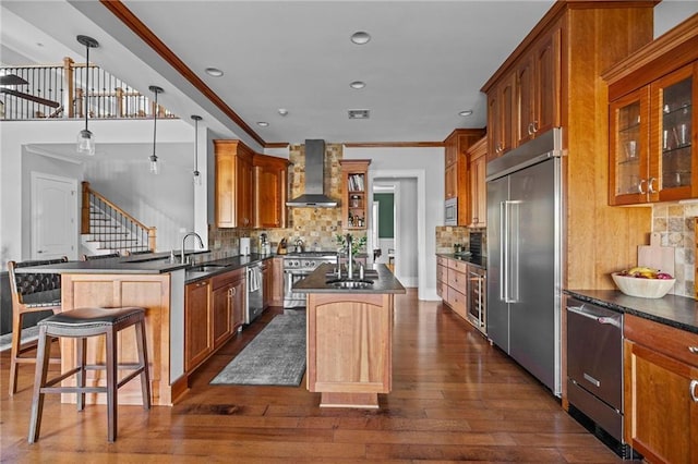 kitchen featuring a breakfast bar area, premium appliances, a kitchen island, decorative light fixtures, and wall chimney exhaust hood