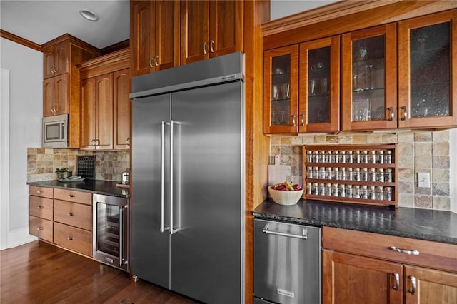 kitchen featuring wine cooler, dark hardwood / wood-style flooring, dark stone counters, decorative backsplash, and built in appliances