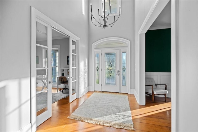 entrance foyer featuring french doors, a chandelier, and light hardwood / wood-style flooring