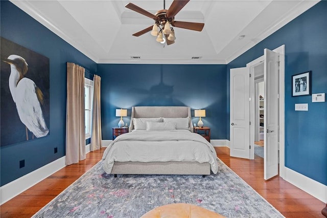 bedroom with ceiling fan, a tray ceiling, and hardwood / wood-style floors