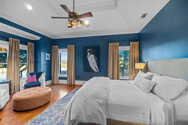bedroom with ceiling fan, wood-type flooring, and a tray ceiling