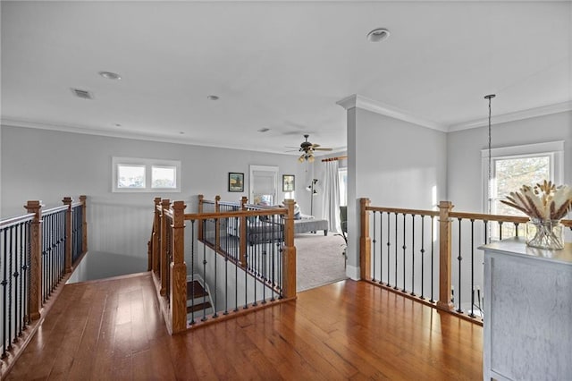hallway with ornamental molding, wood-type flooring, and a healthy amount of sunlight