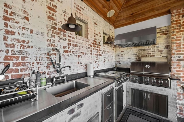 kitchen featuring vaulted ceiling, brick wall, decorative light fixtures, and wall chimney exhaust hood