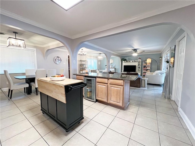 kitchen featuring light tile patterned floors, ornamental molding, beverage cooler, and a kitchen island