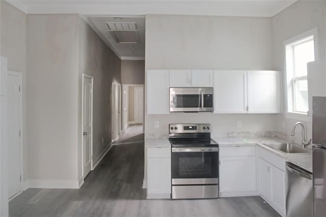 kitchen with sink, white cabinetry, dark hardwood / wood-style flooring, stainless steel appliances, and light stone countertops