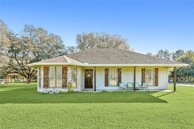 view of front facade with a porch, a front yard, and roof with shingles