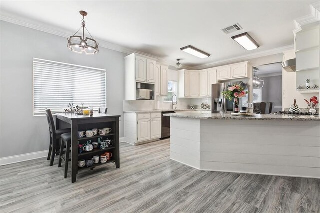 kitchen with decorative light fixtures, white cabinetry, light stone counters, stainless steel appliances, and crown molding