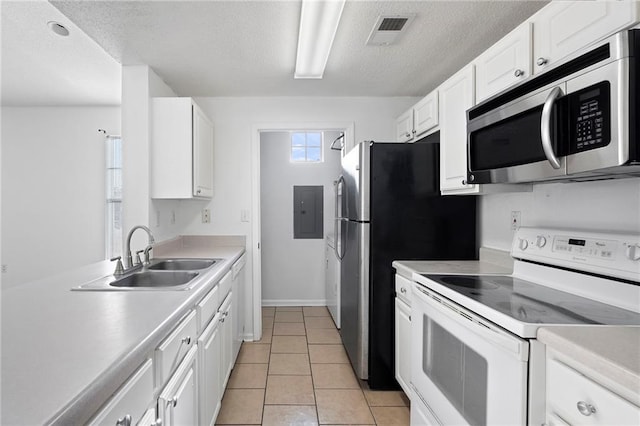 kitchen with electric range, visible vents, a sink, stainless steel microwave, and light countertops