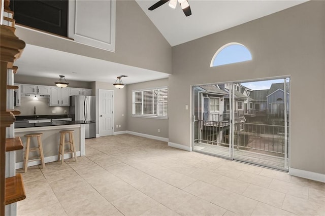 living room with plenty of natural light, high vaulted ceiling, ceiling fan, and light tile patterned flooring