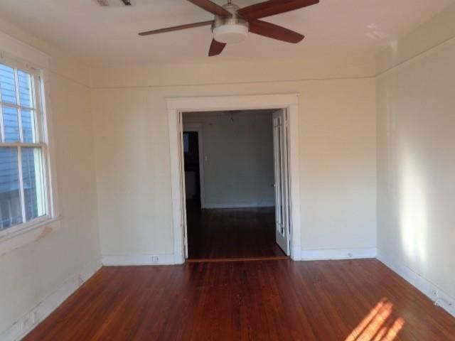 empty room featuring visible vents, baseboards, dark wood finished floors, and a ceiling fan