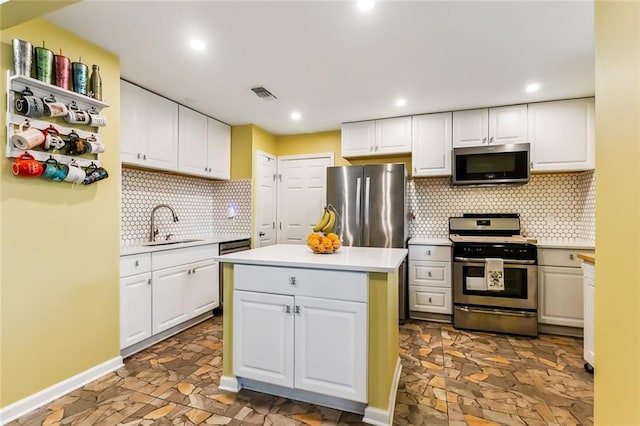 kitchen with light countertops, visible vents, appliances with stainless steel finishes, white cabinets, and a kitchen island