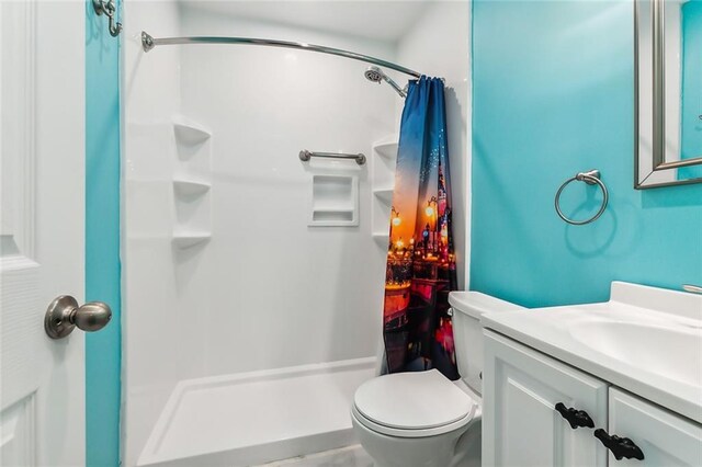 full bathroom with vanity, a shower stall, and toilet
