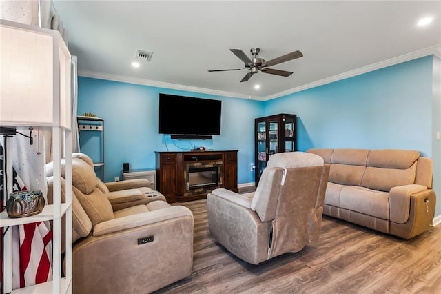 living room featuring a ceiling fan, visible vents, crown molding, and wood finished floors