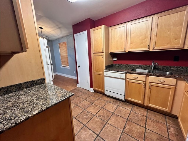 kitchen featuring dark stone countertops, sink, and white appliances