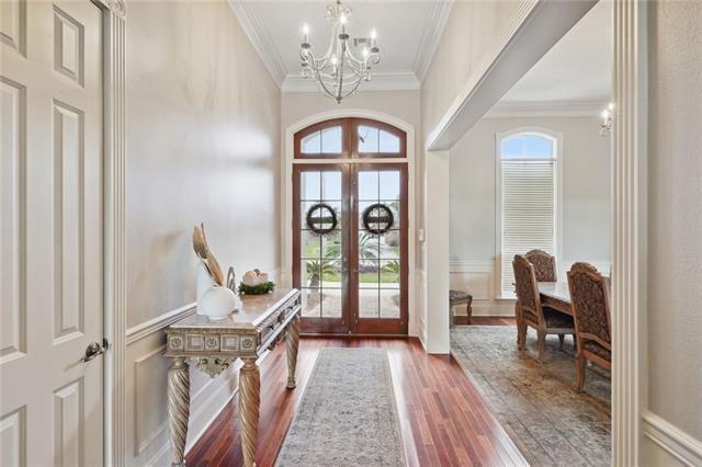 foyer featuring crown molding, wood-type flooring, an inviting chandelier, and french doors