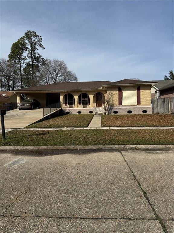 ranch-style home featuring a front lawn and a carport