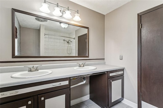 bathroom featuring tile patterned flooring, vanity, a textured ceiling, and a tile shower