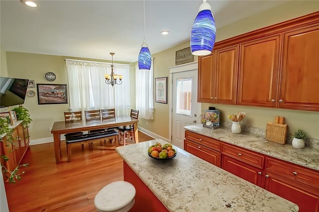 kitchen featuring hanging light fixtures, light hardwood / wood-style flooring, and light stone countertops