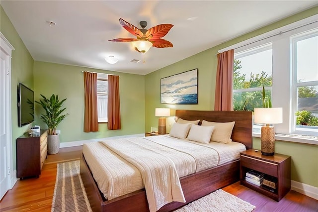 bedroom featuring ceiling fan, multiple windows, and light wood-type flooring