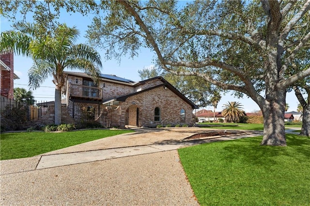 view of front of property featuring a balcony and a front yard