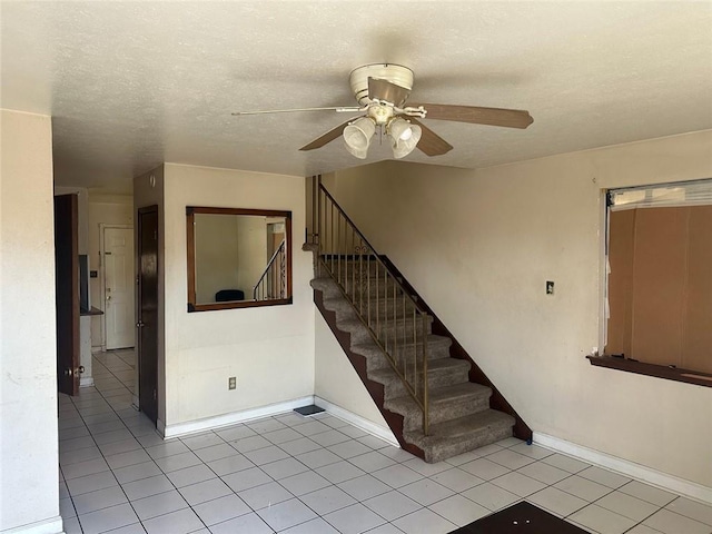 stairway featuring ceiling fan, tile patterned floors, and a textured ceiling