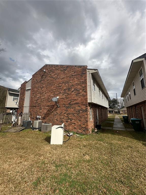 view of property exterior with a yard and central AC