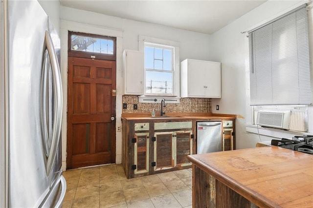 kitchen featuring sink, wooden counters, appliances with stainless steel finishes, white cabinets, and decorative backsplash