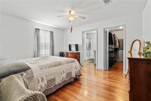 bedroom with light hardwood / wood-style flooring, a walk in closet, ceiling fan, ensuite bath, and a closet