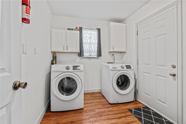 washroom with cabinets, separate washer and dryer, and light hardwood / wood-style flooring