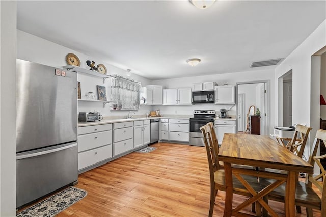 kitchen with white cabinetry, appliances with stainless steel finishes, sink, and light hardwood / wood-style floors