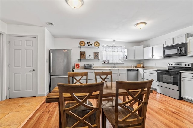 kitchen featuring sink, light hardwood / wood-style flooring, stainless steel appliances, and white cabinets