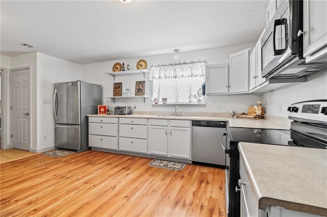 kitchen featuring stainless steel appliances, white cabinetry, sink, and light hardwood / wood-style flooring