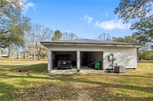 exterior space featuring an outbuilding, a garage, central AC unit, and a lawn