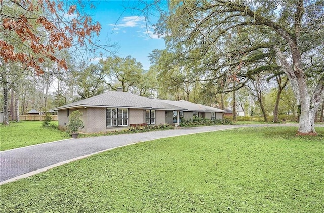 ranch-style home with driveway, a front lawn, and brick siding