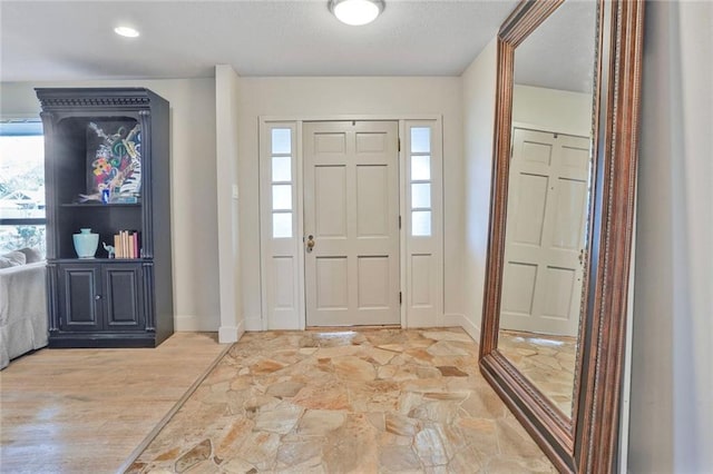 entrance foyer with stone finish flooring, a textured ceiling, and baseboards