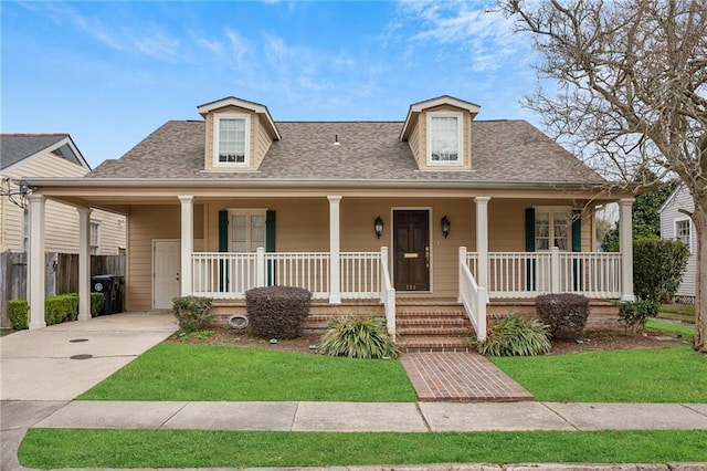 view of front of house with roof with shingles, a front lawn, and covered porch