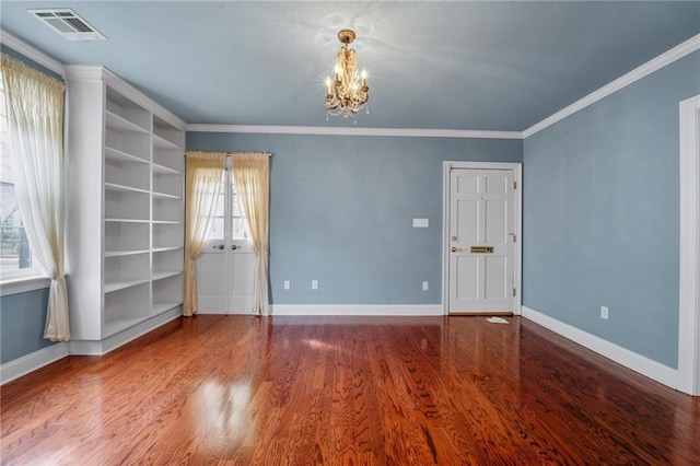 spare room featuring an inviting chandelier, crown molding, and wood-type flooring