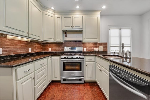 kitchen with tasteful backsplash, dark stone countertops, white cabinets, stainless steel appliances, and dark wood-type flooring