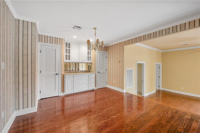 unfurnished living room featuring ornamental molding, hardwood / wood-style floors, and a notable chandelier