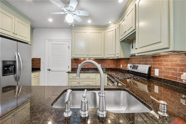 kitchen with stainless steel appliances, sink, decorative backsplash, and dark stone countertops