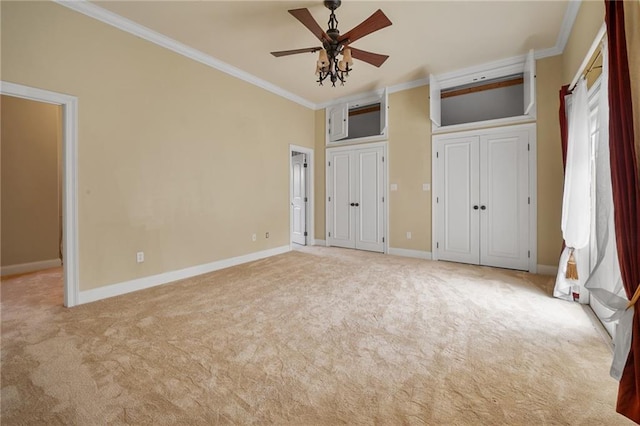 unfurnished bedroom with multiple closets, ceiling fan, ornamental molding, and light carpet