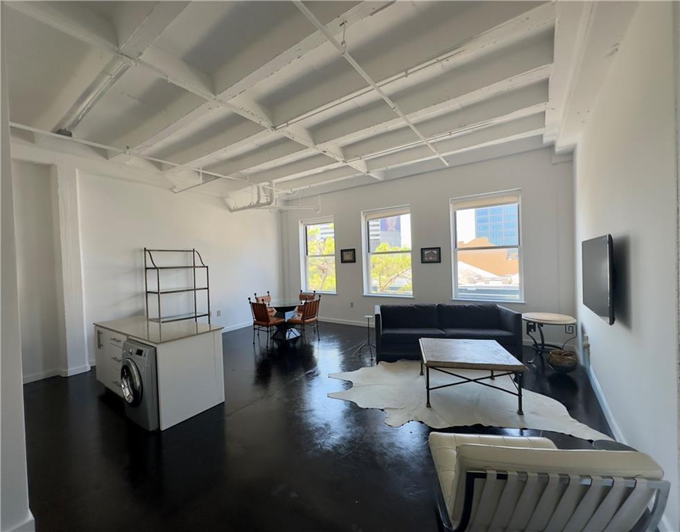 living area featuring baseboards, concrete flooring, and washer / clothes dryer