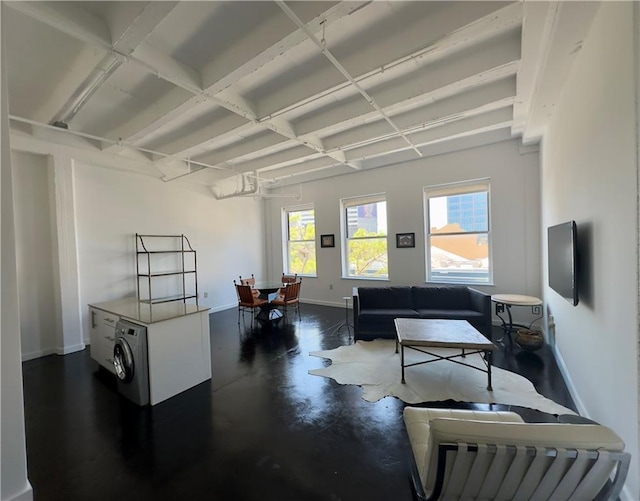 living area featuring baseboards, concrete flooring, and washer / clothes dryer