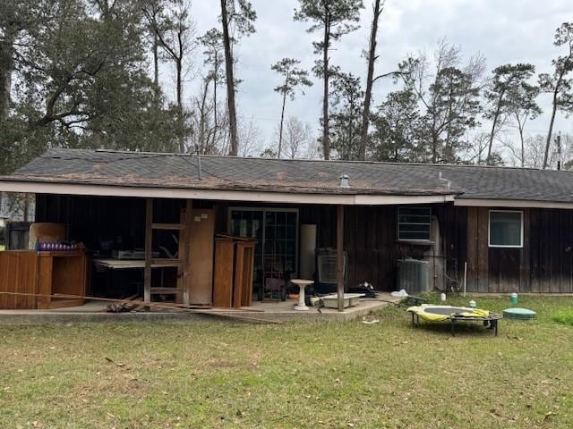 rear view of house featuring central AC unit and a yard