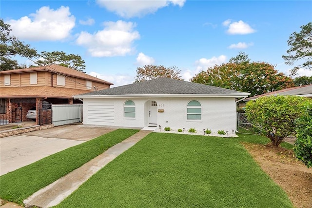 view of front of property with driveway, a front lawn, fence, roof with shingles, and brick siding